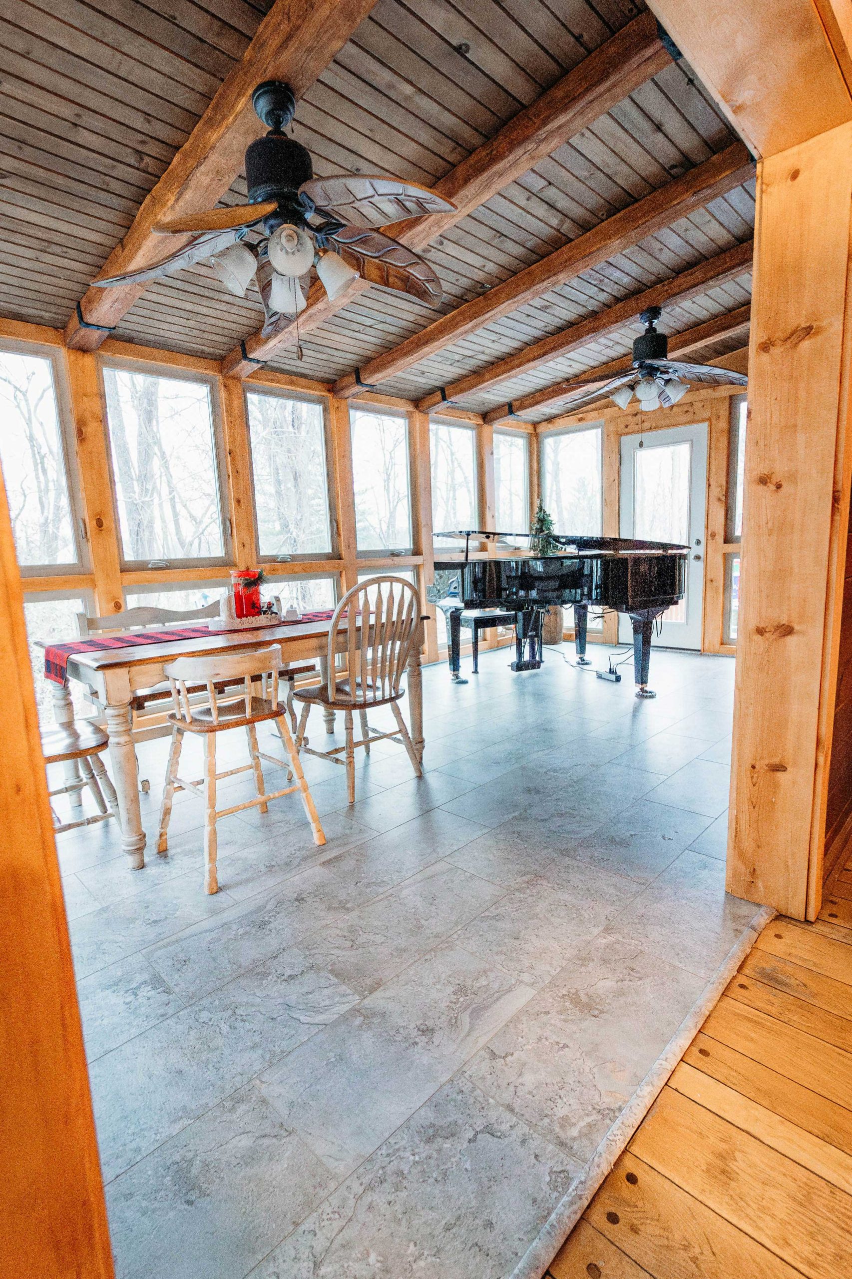 Three-season porch featuring timber framing, ceiling fans, and tile flooring built by Mueller Remodeling.