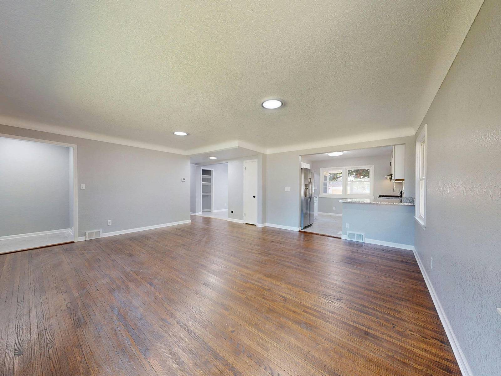 Renovated open living space featuring hardwood flooring, recessed lighting, and fresh gray walls completed by Mueller Remodeling.