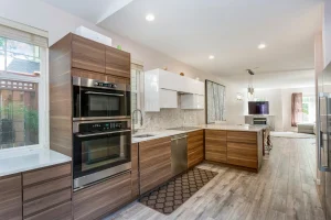 A modern open-concept kitchen with custom wood cabinetry and sleek appliances showcasing a successfully completed complex home remodeling project.