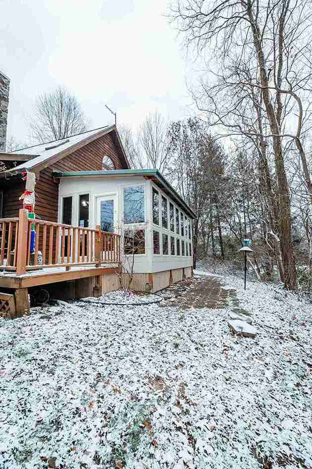 Custom enclosed porch addition with large multi-pane windows expands living space and complements the home's exterior design.
