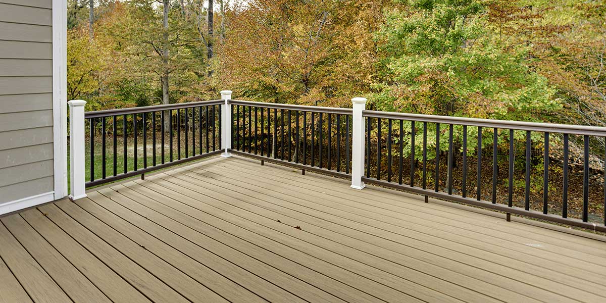 A modern composite deck featuring black metal railing balusters and white posts overlooking a scenic forest in Loveland, OH.
