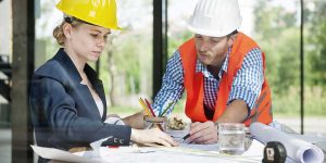 General contractors reviewing building blueprints together at a job site to streamline planning and avoid costly construction delays.